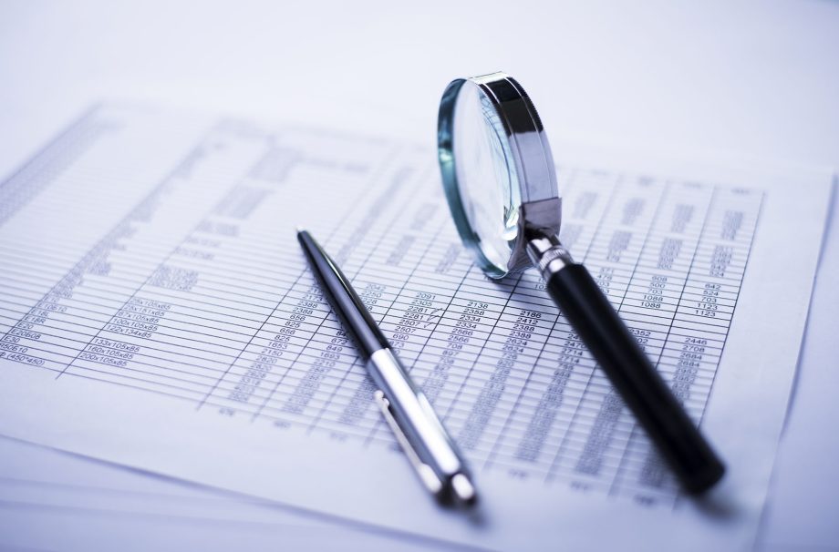 Conceptual image analysis of financial statements, documents, dollars, magnifying glass and pen on office desk